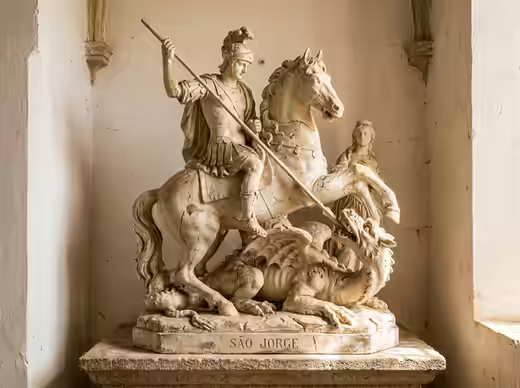 Oração de São Jorge — imagem de pedra do santo guerreiro sobre o dragão, com o nome gravado na base